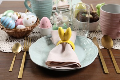 Photo of Festive table setting with napkin ring in shape of bunny ears, closeup. Easter celebration