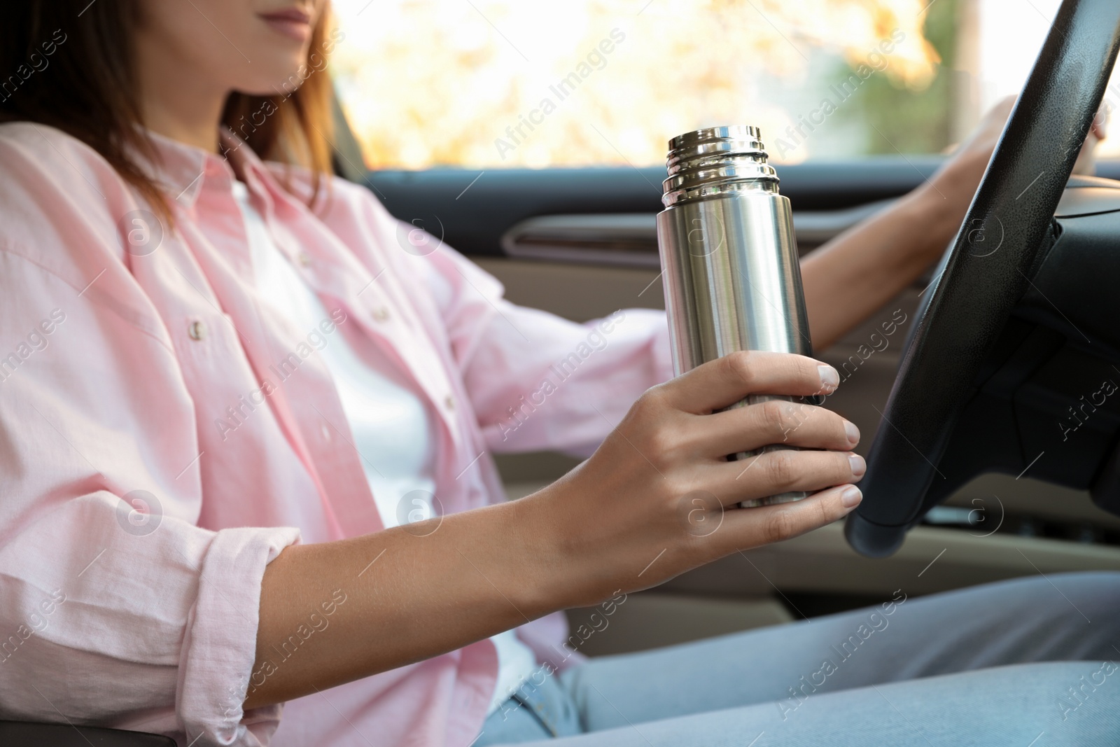 Photo of Woman with thermos driving car, closeup view