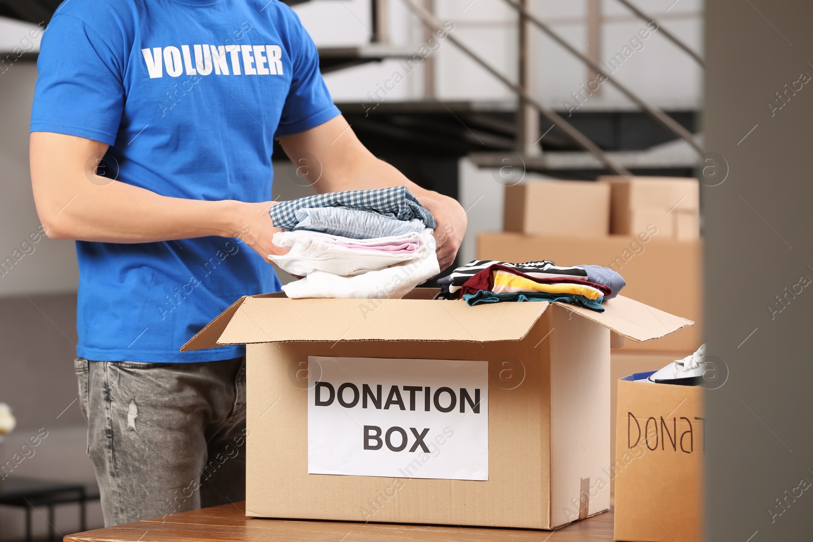 Photo of Male volunteer putting clothes in donation box indoors