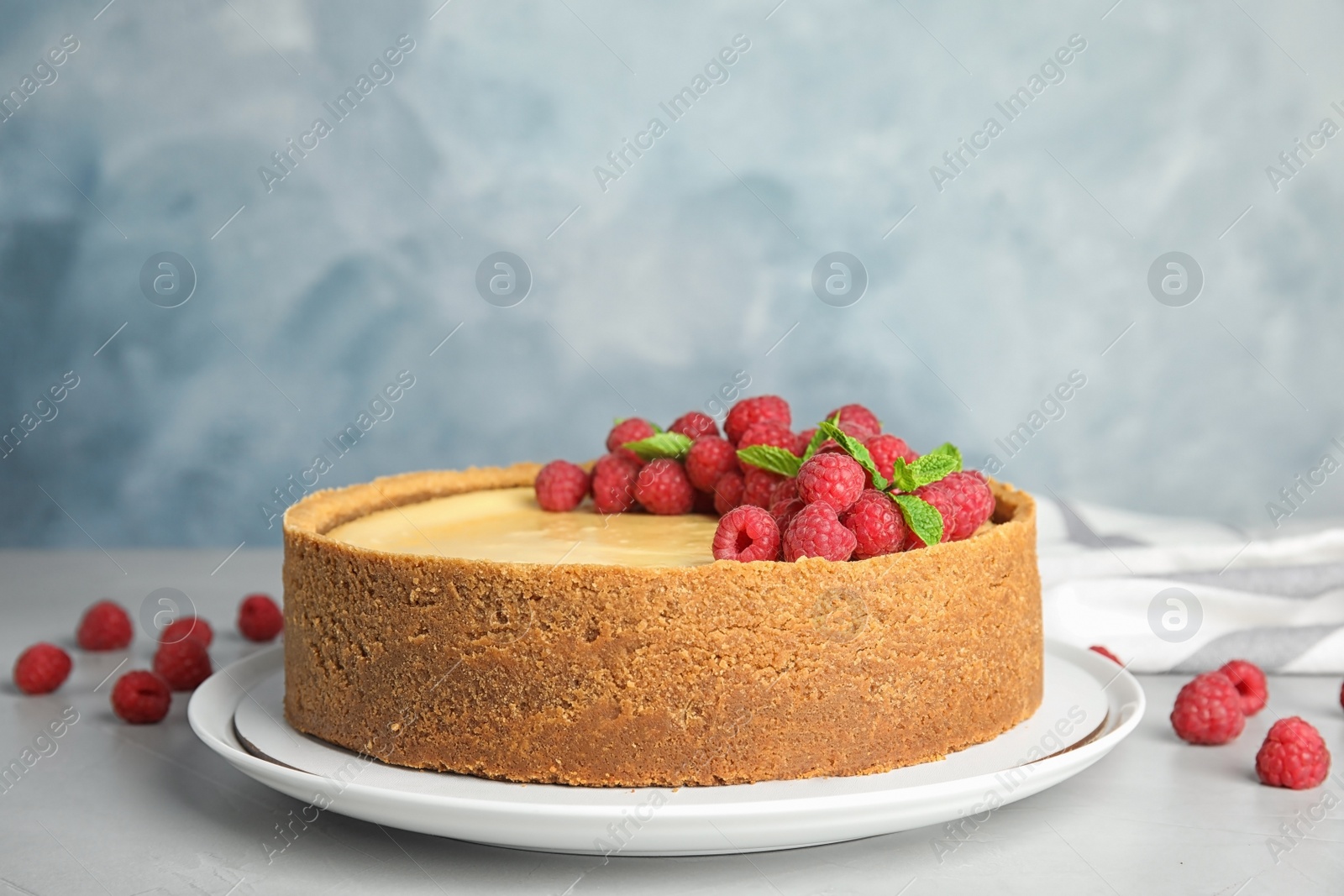 Photo of Dessert plate with delicious raspberry cake on table against blue background. Space for text