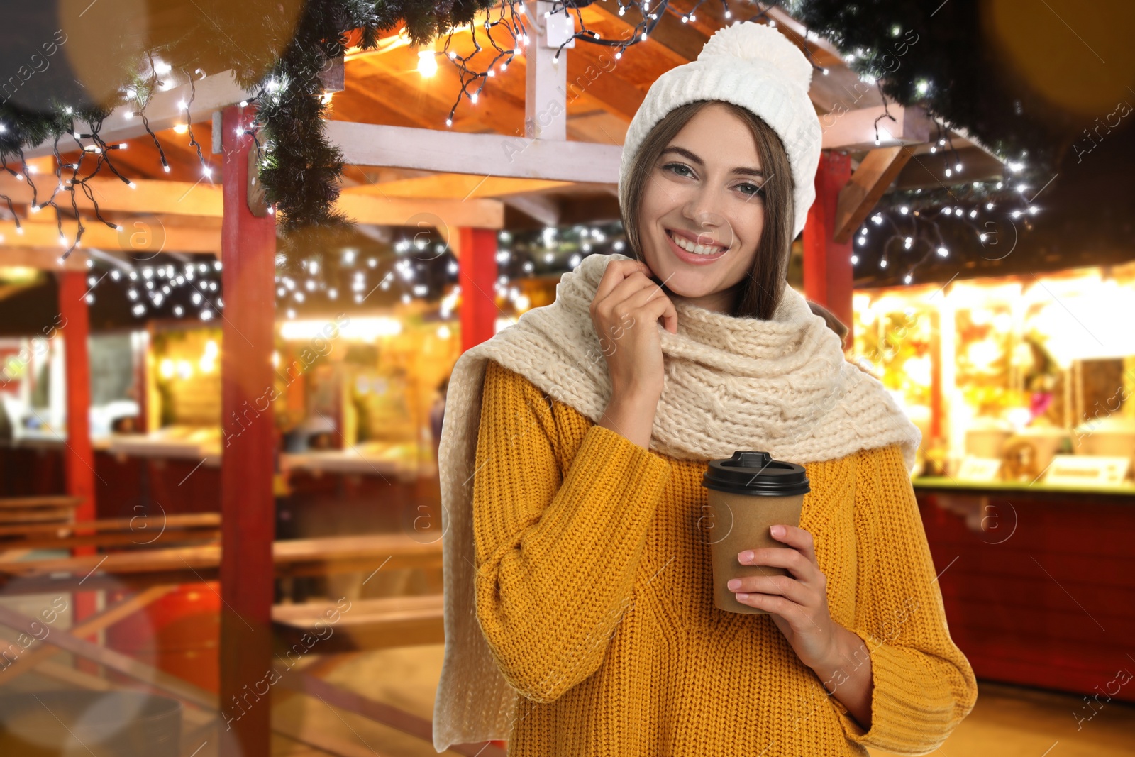 Image of Happy beautiful woman with paper cup of mulled wine at Christmas fair