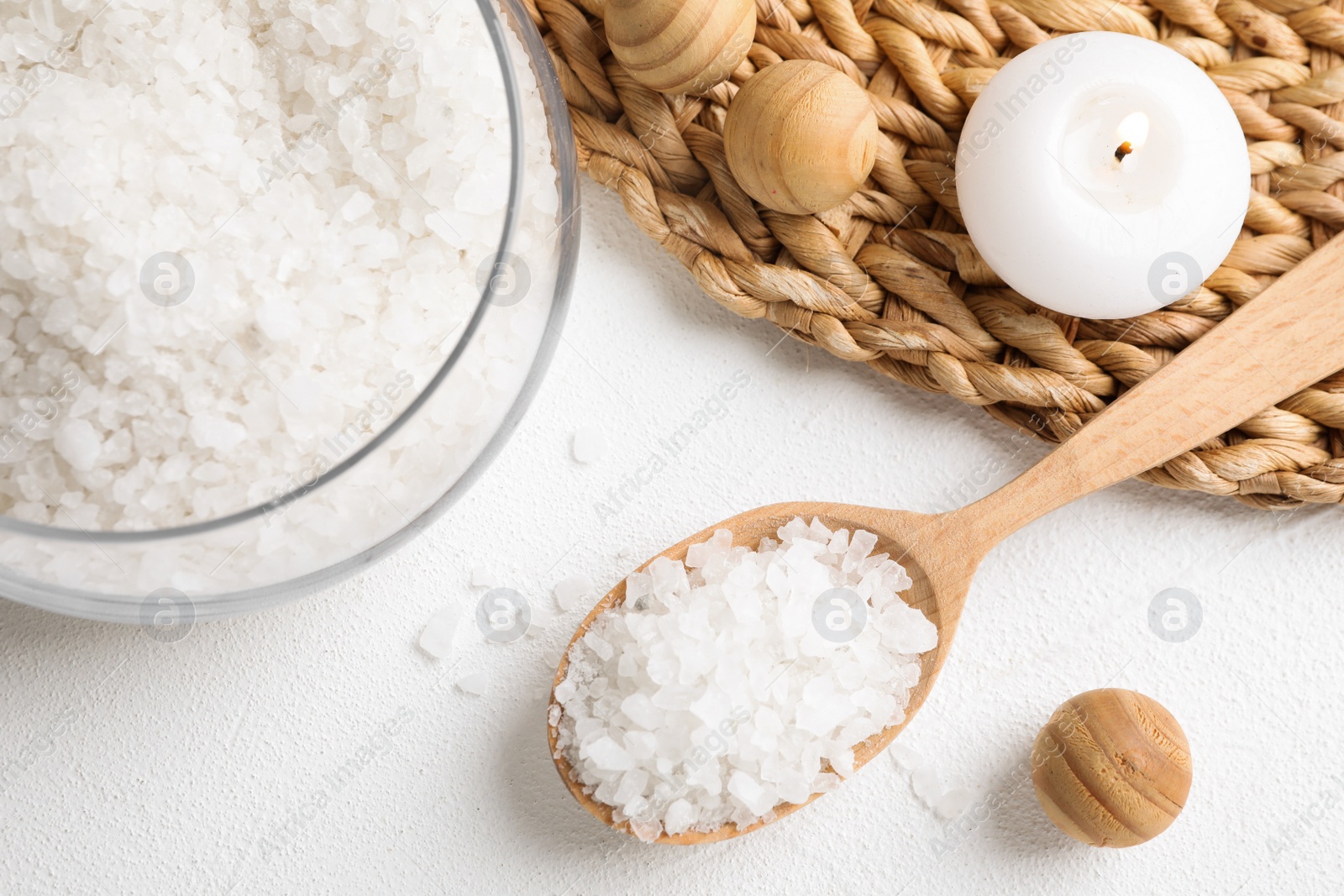 Photo of Wooden spoon with sea salt for spa scrubbing procedure on white table, flat lay