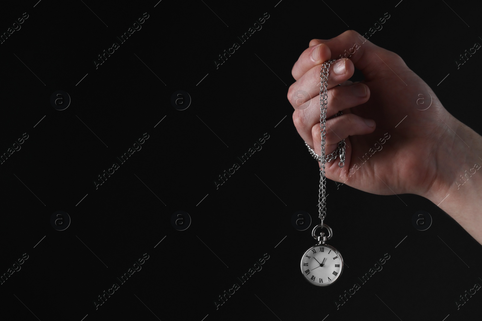 Photo of Man holding chain with elegant pocket watch on black background, closeup. Space for text