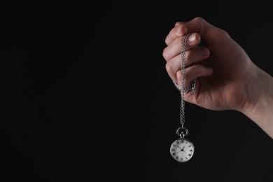 Photo of Man holding chain with elegant pocket watch on black background, closeup. Space for text