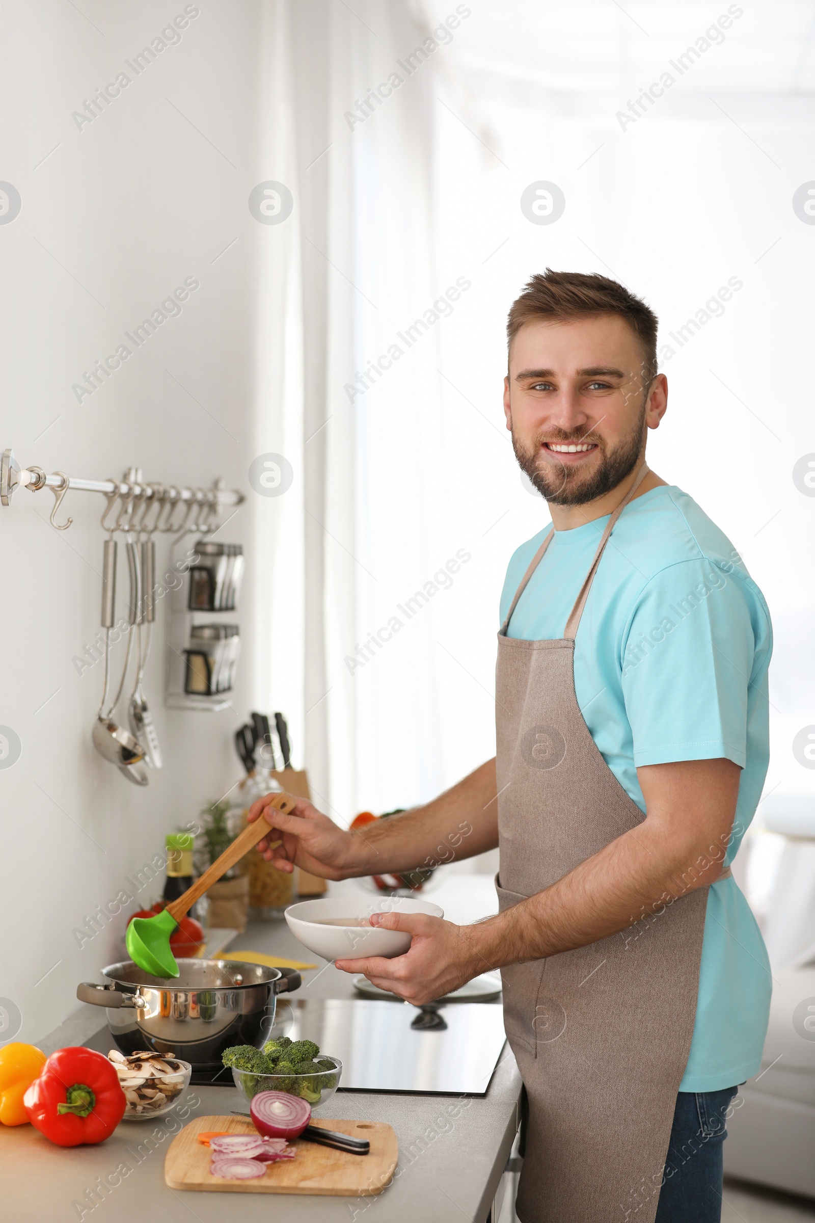 Photo of Young man pouring delicious soup into bowl at home