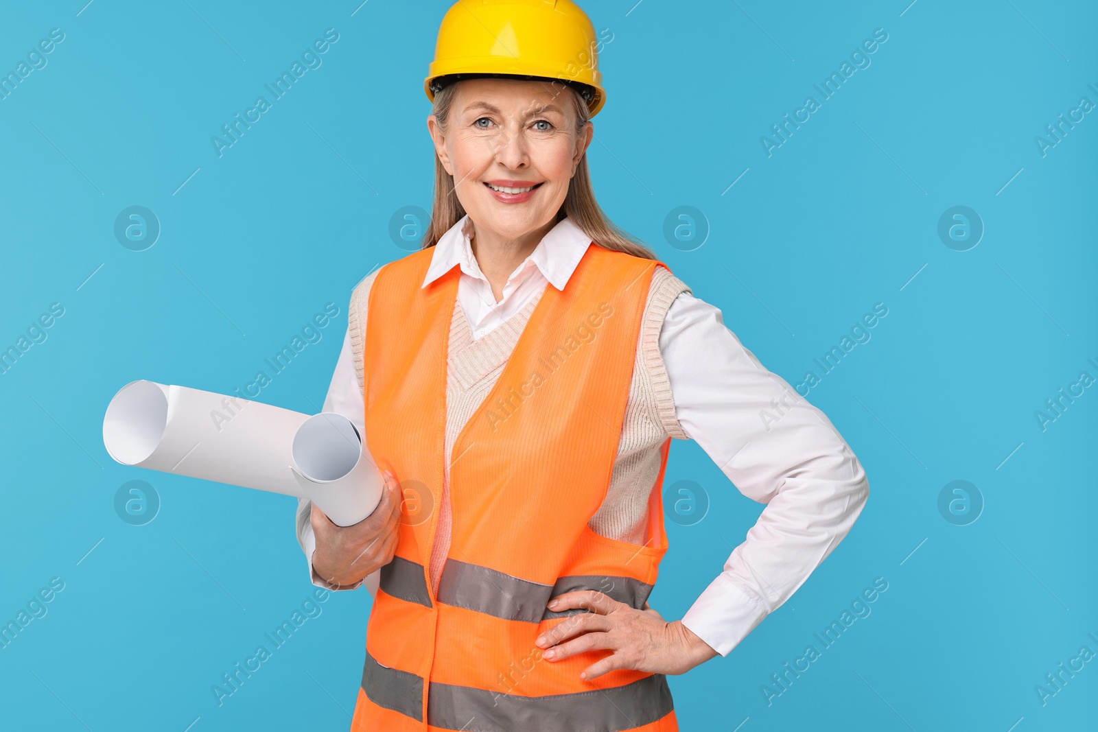 Photo of Architect in hard hat with drafts on light blue background