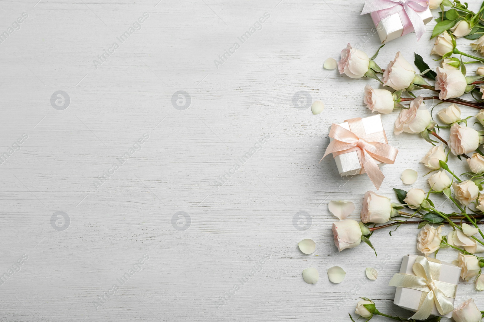 Photo of Flat lay composition with beautiful roses and gift boxes on wooden background. Space for text