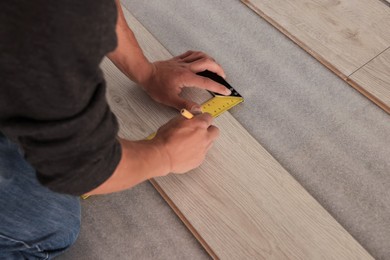 Photo of Professional worker using ruler during installationlaminate flooring, closeup. Space for text