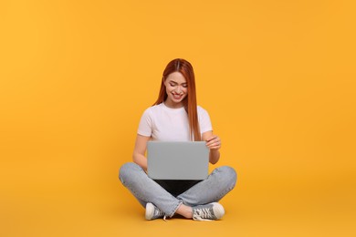 Photo of Smiling young woman with laptop on yellow background