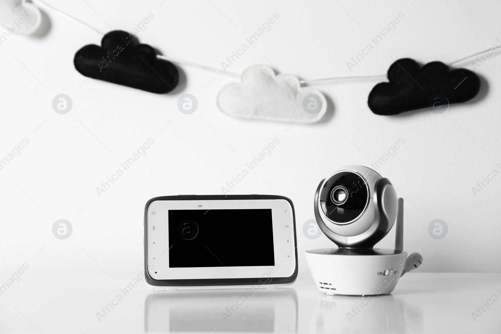 Photo of Modern CCTV security camera, monitor and nursery garland on background. Space for text