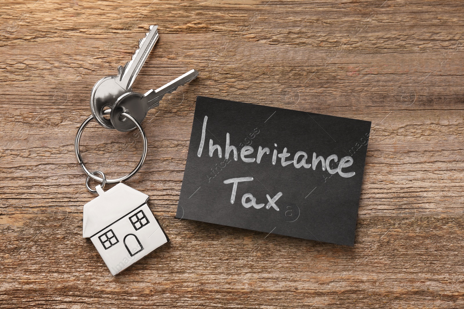 Photo of Inheritance Tax. Card and keys with key chain in shape of house on wooden table, top view