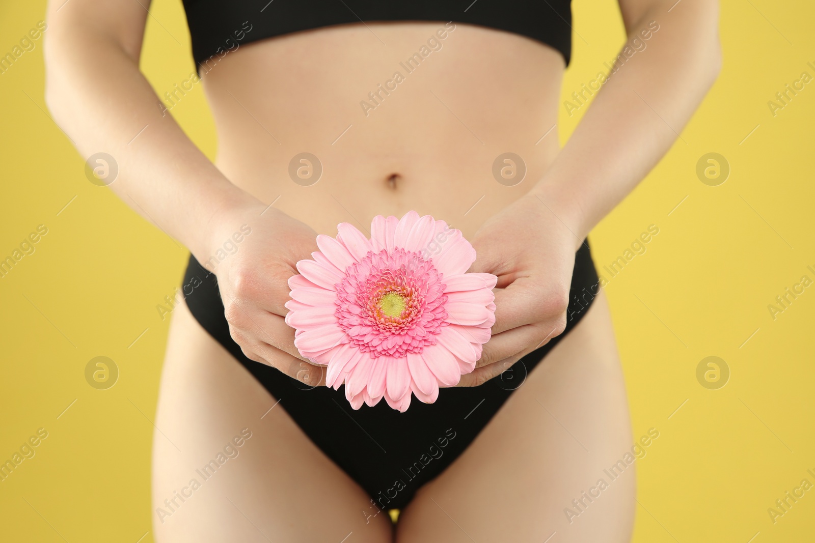 Photo of Gynecology. Woman in underwear with gerbera flower on yellow background, closeup