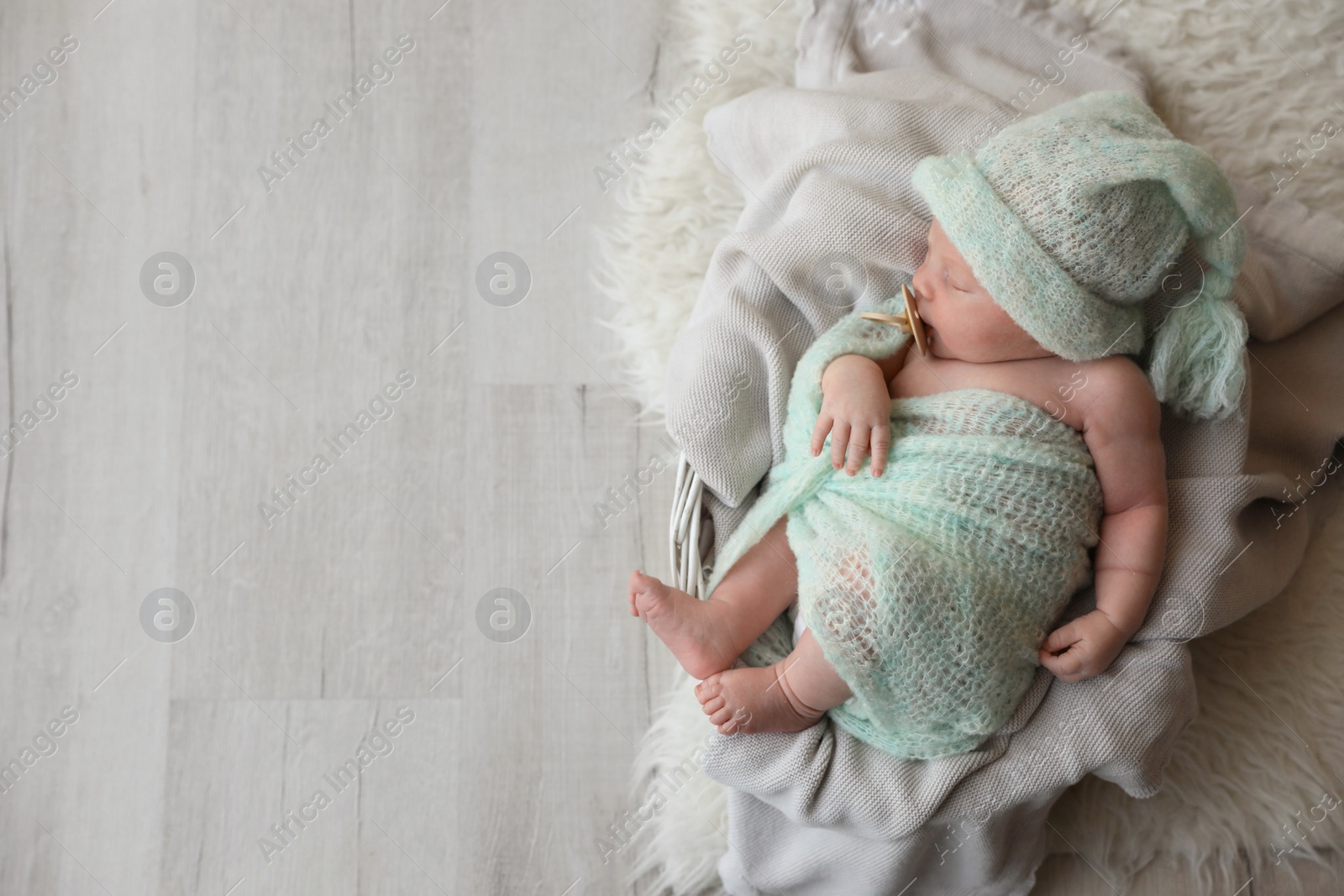 Photo of Cute newborn baby sleeping on plaid in basket, top view. Space for text