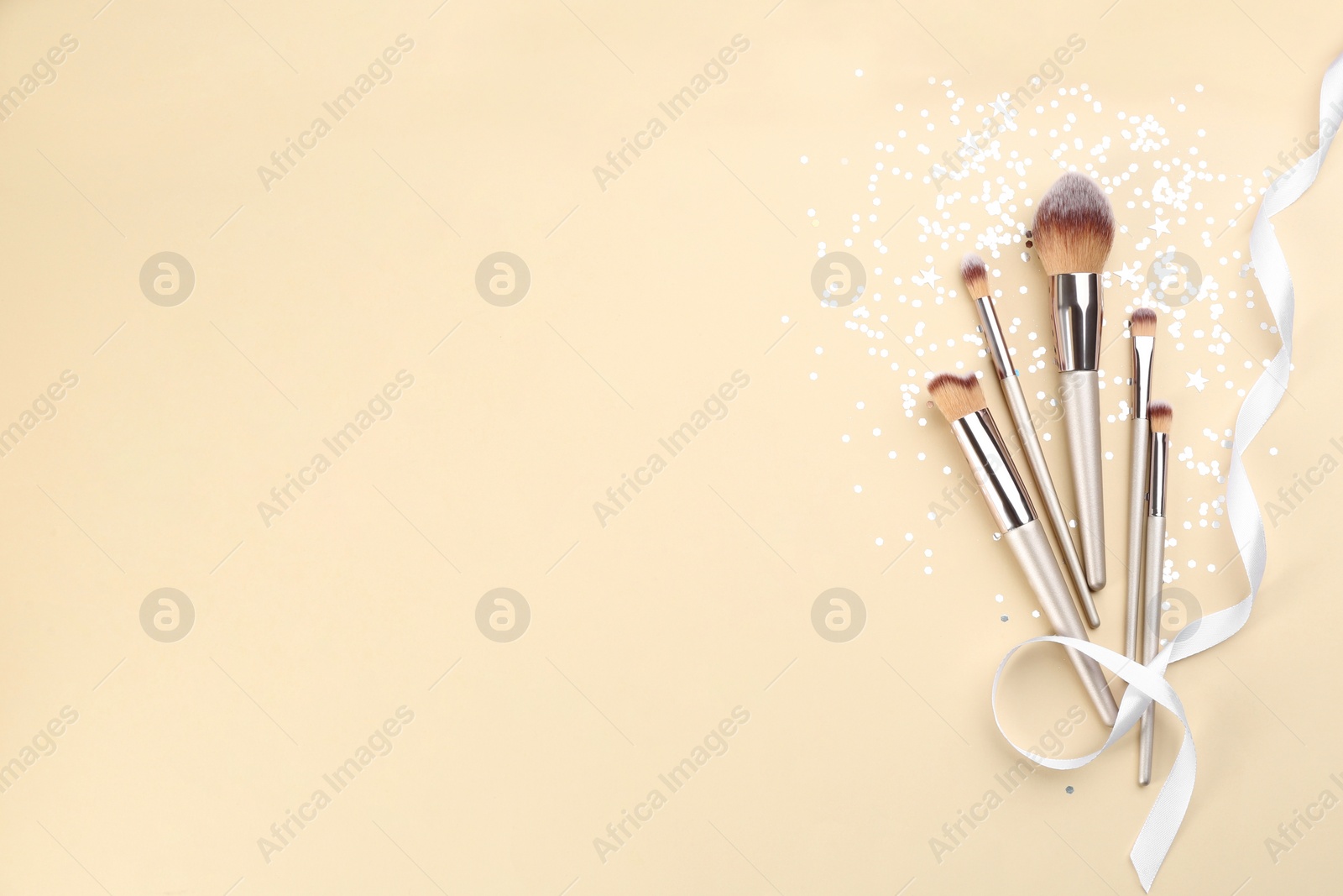 Photo of Flat lay composition with makeup brushes on beige background, space for text