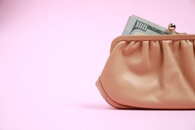Stylish beige leather purse with dollar banknote on pink background, space for text
