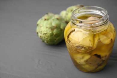 Photo of Pickled and fresh artichokes on grey wooden table, closeup. Space for text
