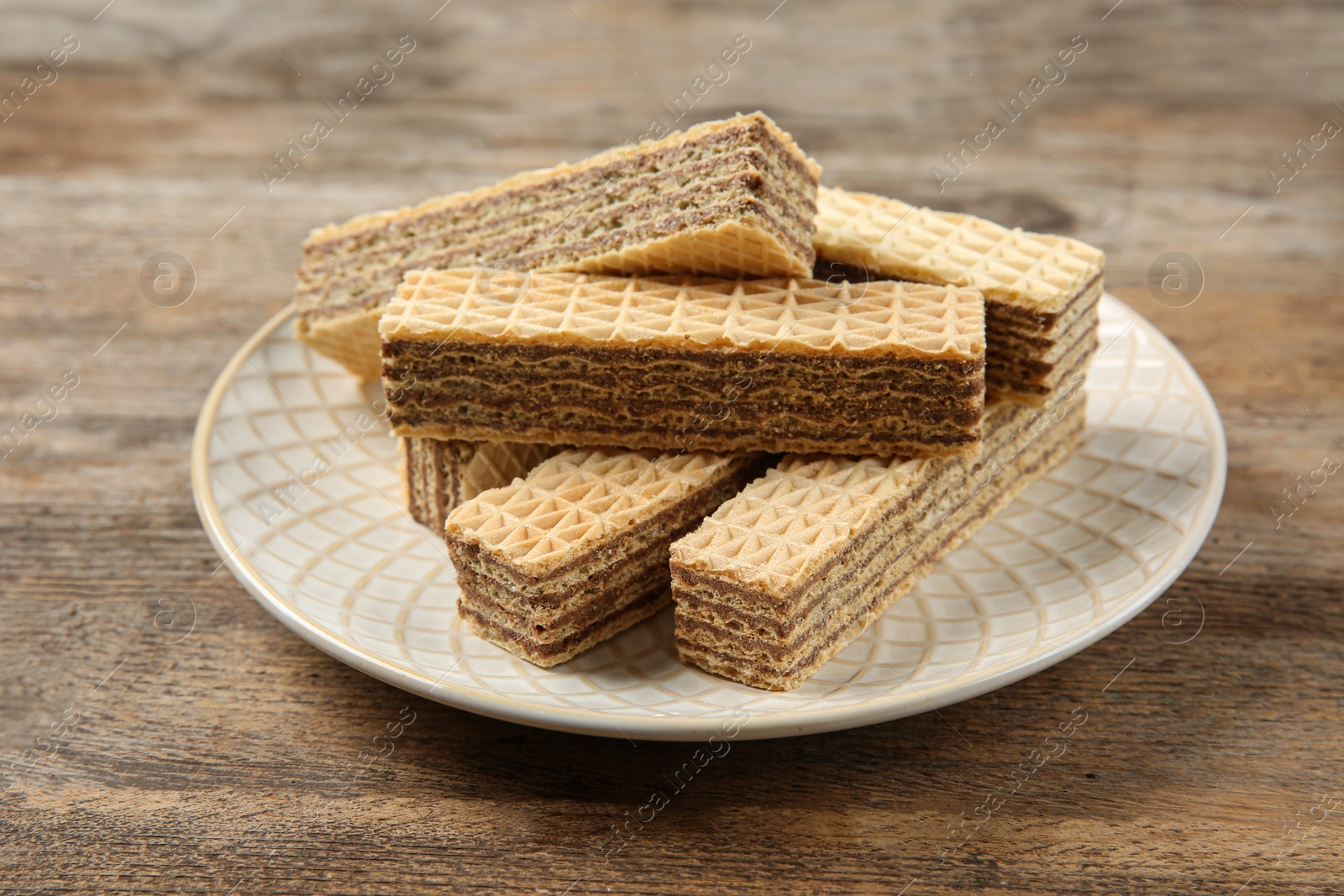 Photo of Plate of delicious wafers on brown wooden background