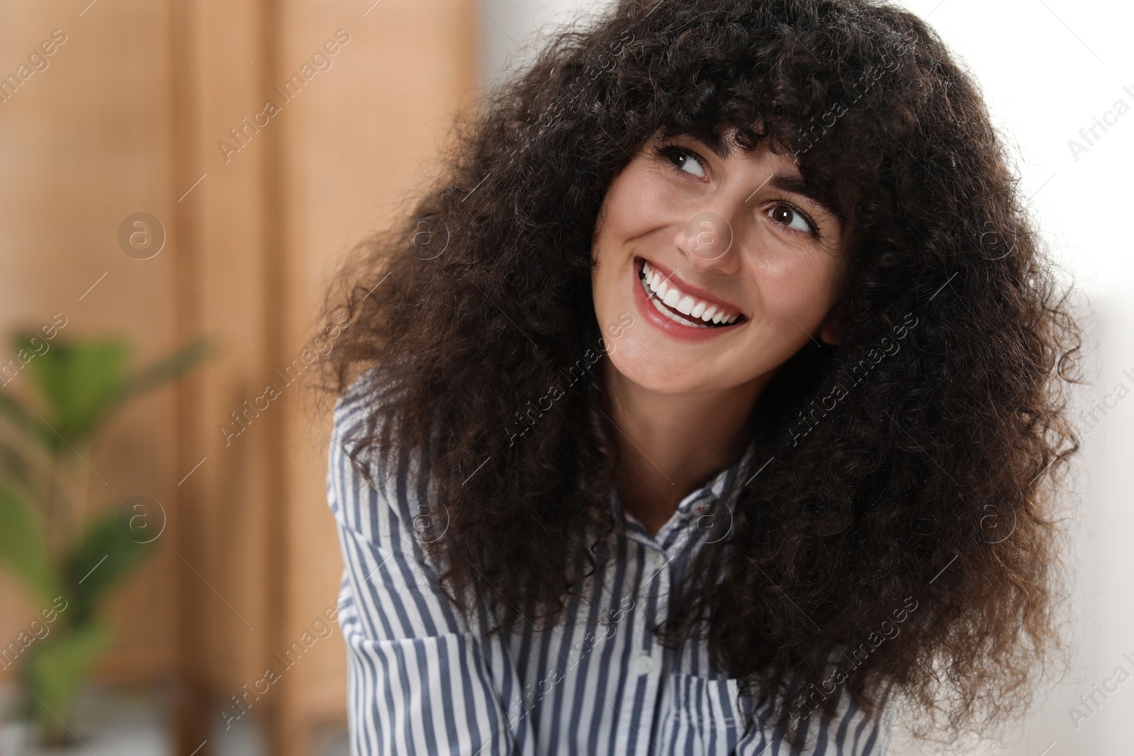 Photo of Portrait of beautiful woman with curly hair indoors. Attractive lady smiling and posing for camera. Space for text