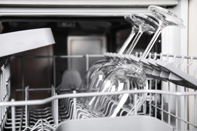 Photo of Open clean dishwasher with glasses, closeup. Home appliance