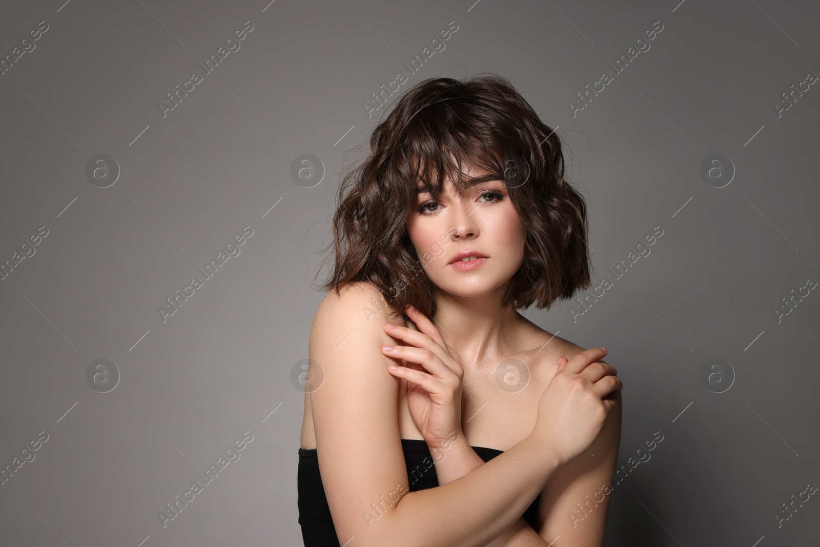 Photo of Portrait of beautiful young woman with wavy hairstyle on grey background