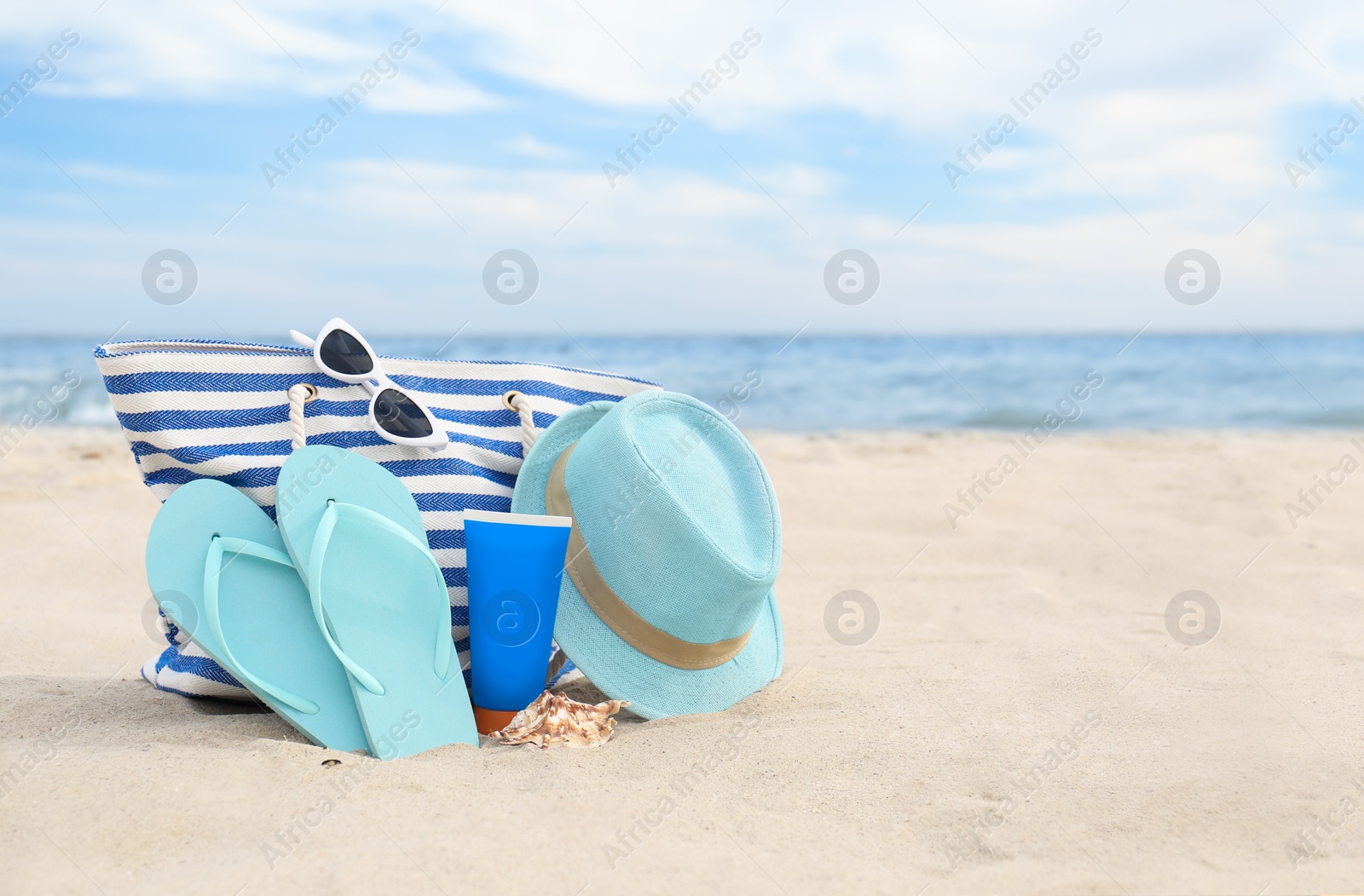 Photo of Different stylish beach objects on sand near sea, space for text