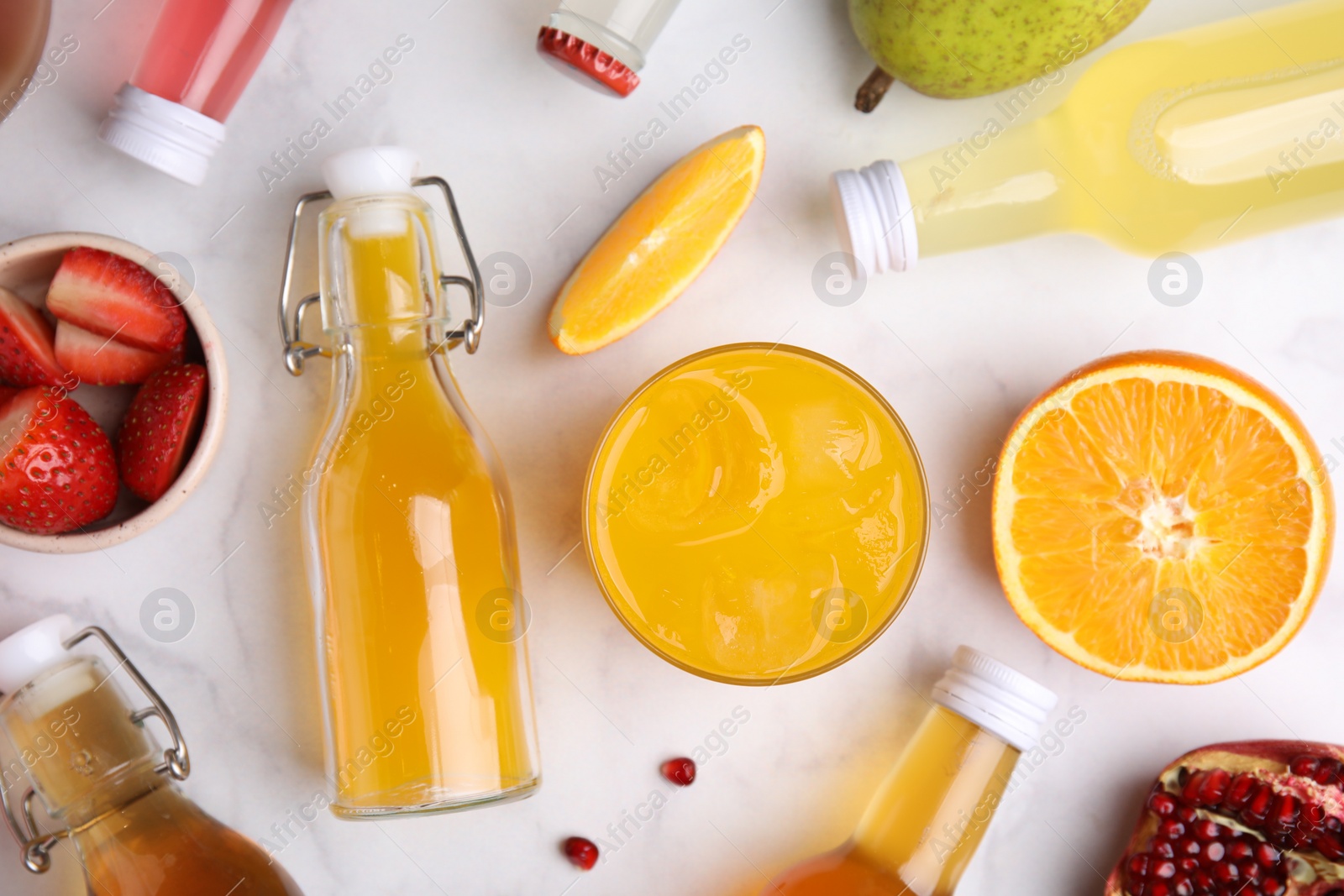 Photo of Tasty kombucha in bottles, glass and fresh fruits on white marble table, flat lay