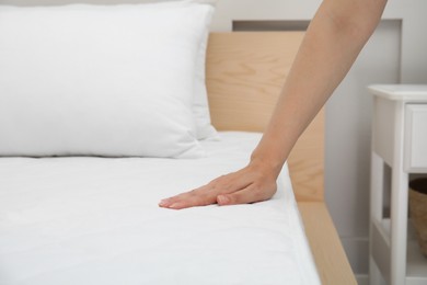 Photo of Woman touching soft white mattress on bed indoors, closeup