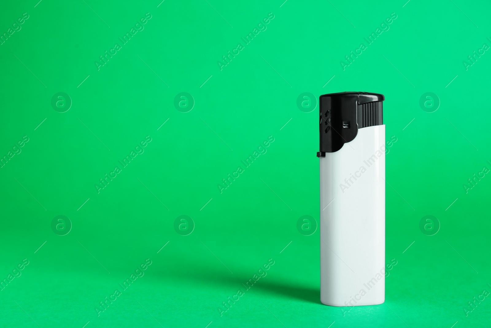Photo of Stylish small pocket lighter on green background, space for text