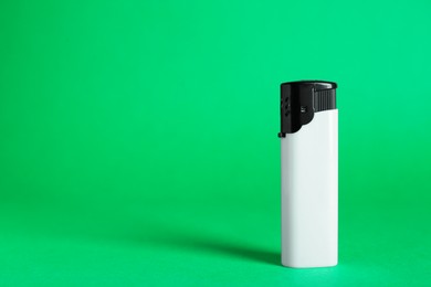 Photo of Stylish small pocket lighter on green background, space for text