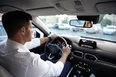 Photo of Man driving his modern luxury car, view from backseat