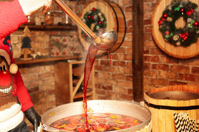 Photo of Seller pouring tasty aromatic mulled wine at winter fair, closeup