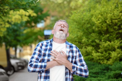 Photo of Mature man having heart attack, outdoors