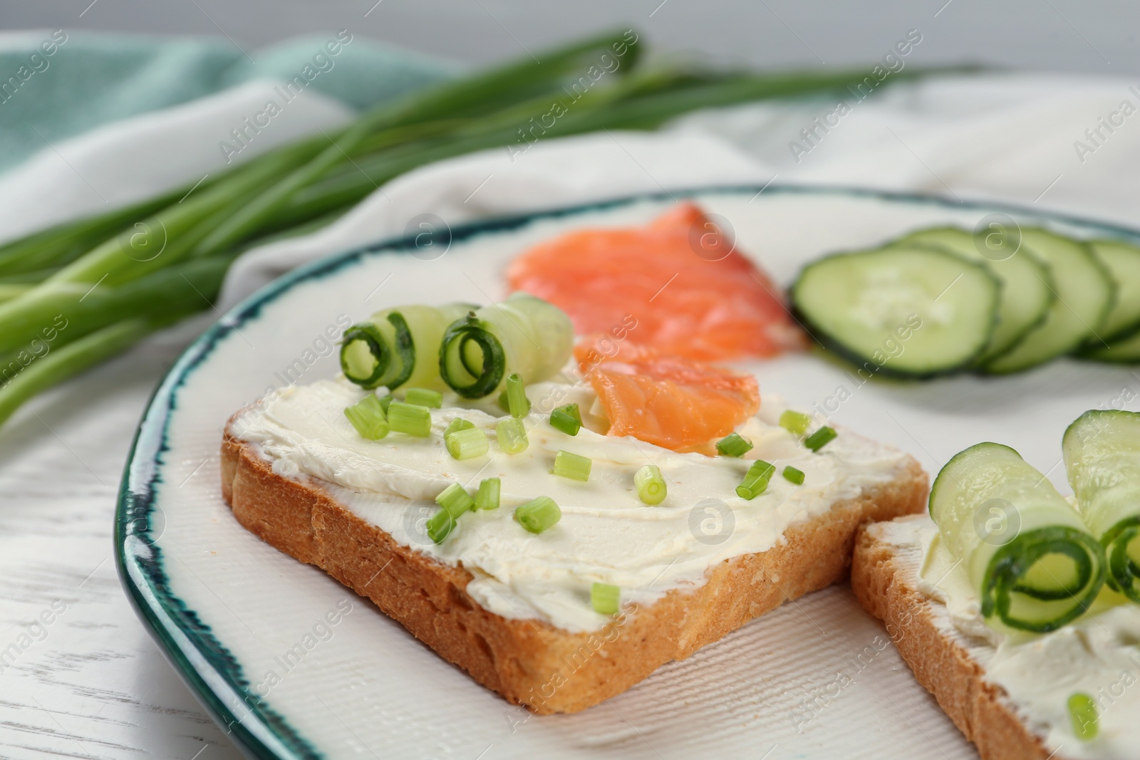 Photo of Toasted bread with cream cheese, salmon and cucumber on plate, closeup