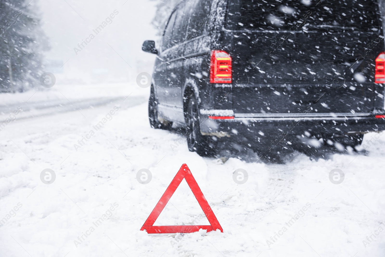 Photo of Emergency stop sign and modern car on snowy road