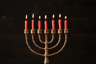 Photo of Golden menorah with burning candles on blurred background