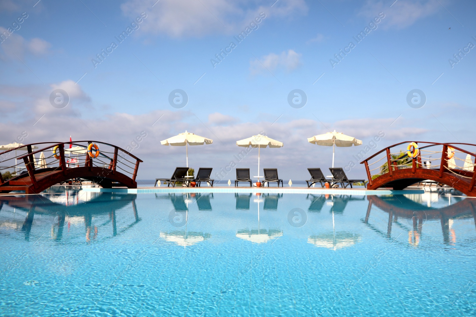 Photo of Chaise longues and beach parasols near outdoor swimming pool at resort