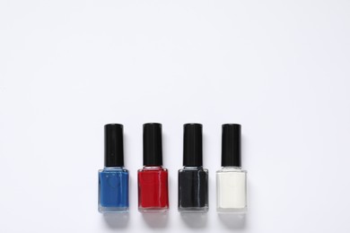 Photo of Nail polishes on white background, flat lay. Space for text