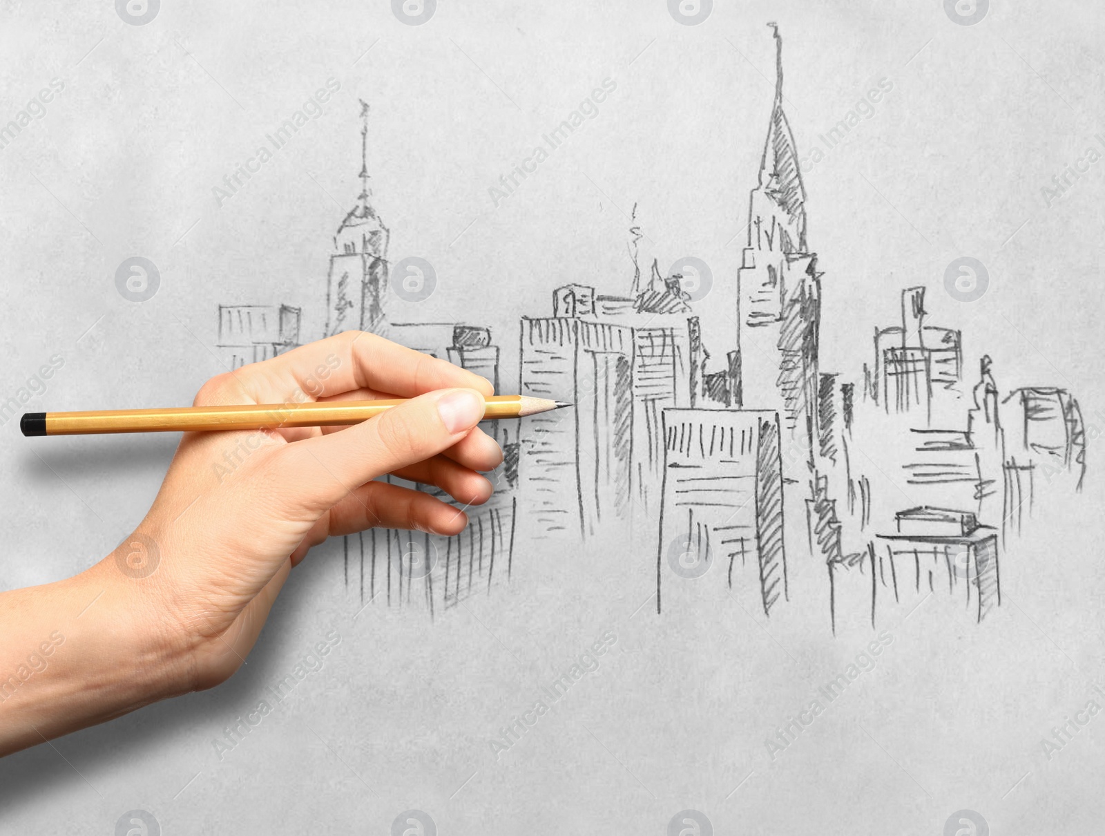 Image of Woman drawing sketch of cityscape with graphite pencil on white paper, closeup