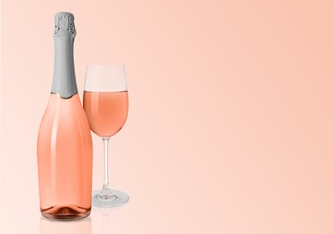 Image of Bottle and glass of delicious rose wine on pink background. Space for text