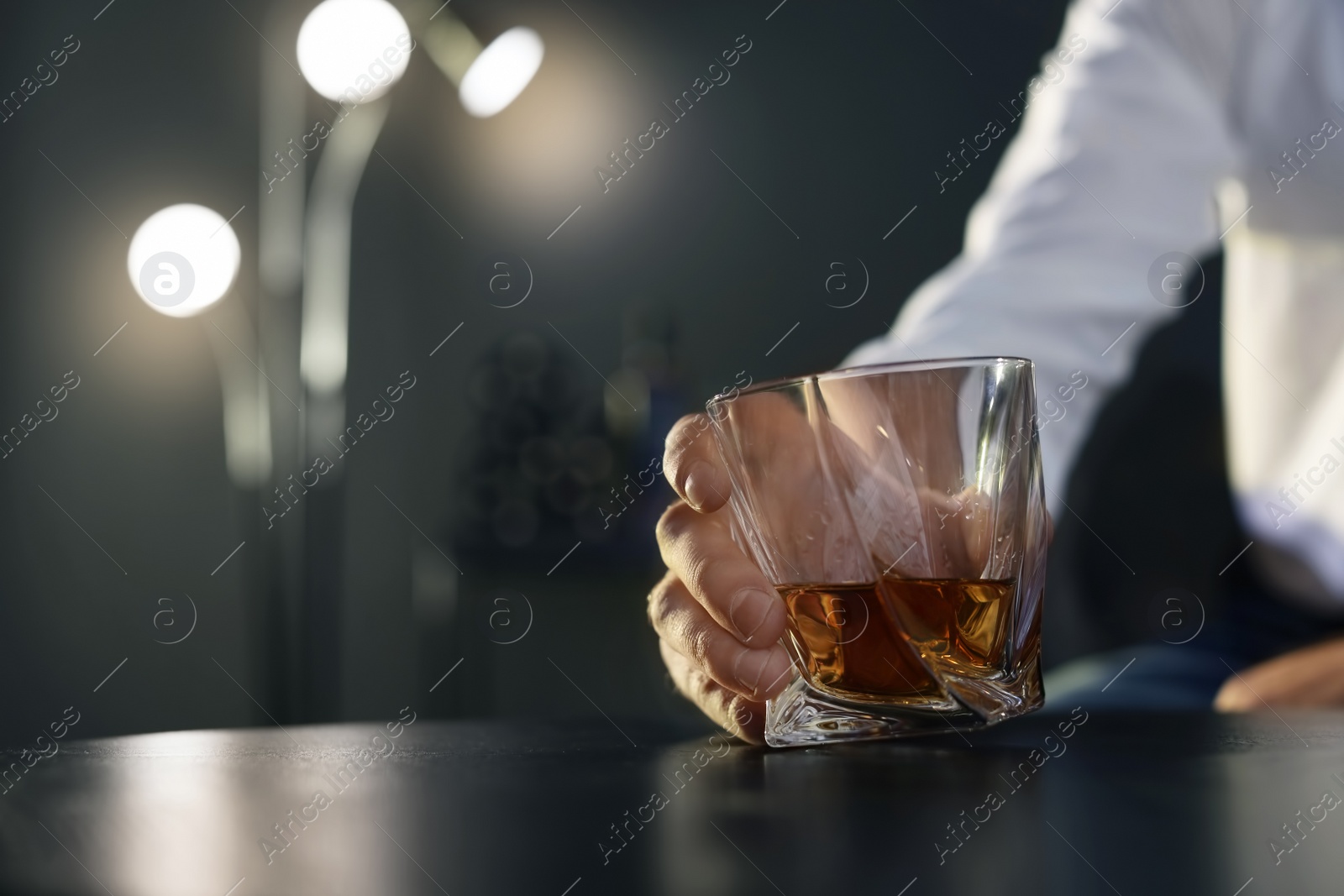 Photo of Man holding glass with whiskey at table, closeup. Space for text