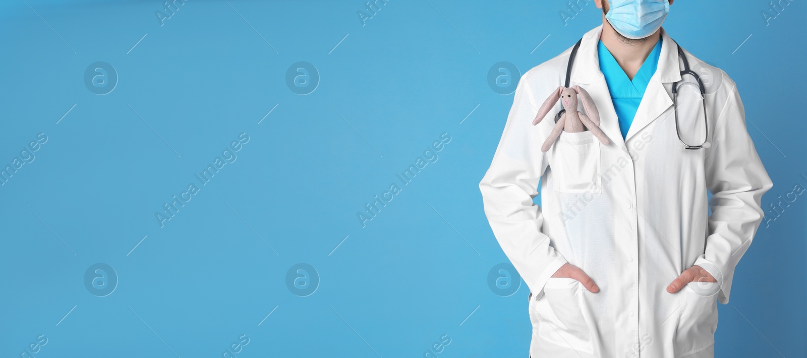 Photo of Pediatrician with toy bunny and stethoscope on light blue background, closeup. Space for text