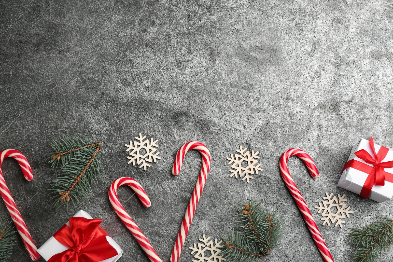 Photo of Flat lay composition with candy canes and Christmas decor on grey table. Space for text