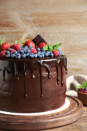 Photo of Freshly made delicious chocolate cake decorated with berries on wooden table