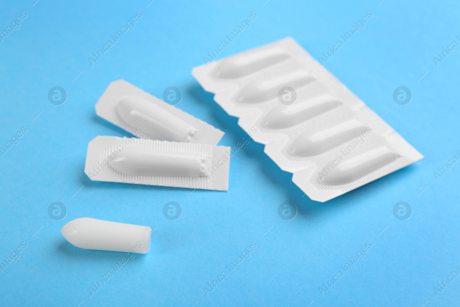 Photo of Suppositories on light blue background. Hemorrhoid treatment