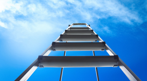 Image of Metal stepladder against blue sky with clouds, low angle view. Banner design 