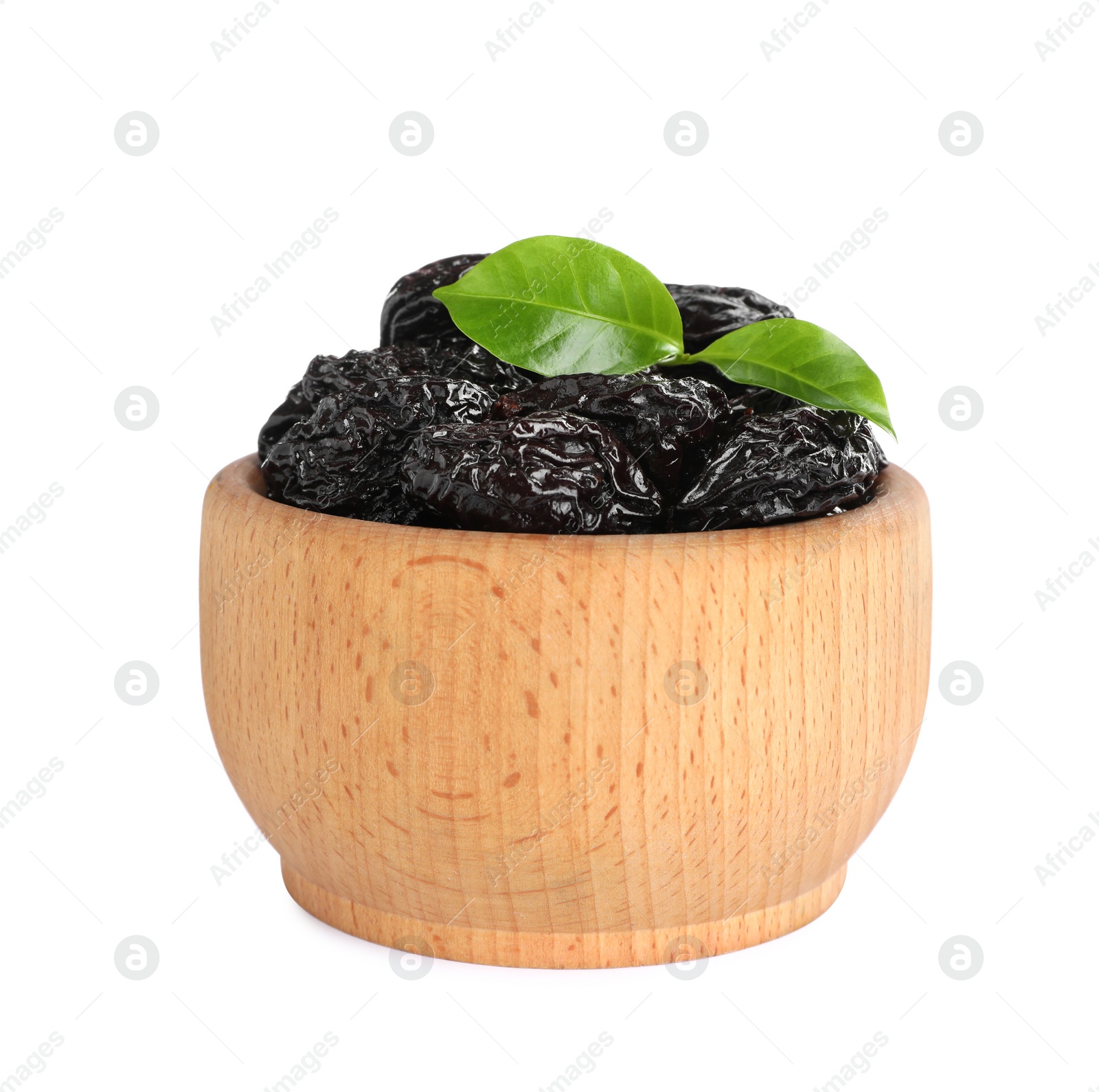 Photo of Wooden bowl with sweet dried prunes and green leaves isolated on white