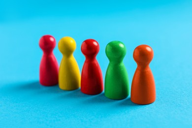 Photo of Colorful pawns on light blue background, closeup. Social inclusion concept