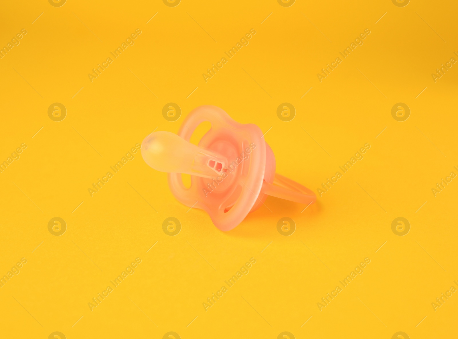 Photo of One new baby pacifier on orange background