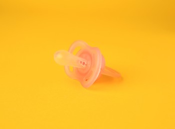 One new baby pacifier on orange background