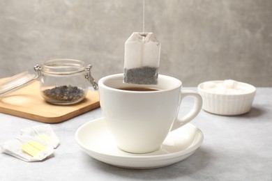 Photo of Tea brewing. Putting tea bag into cup on light table, closeup